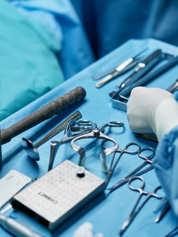 Surgical tools on table with nurse's gloved hand