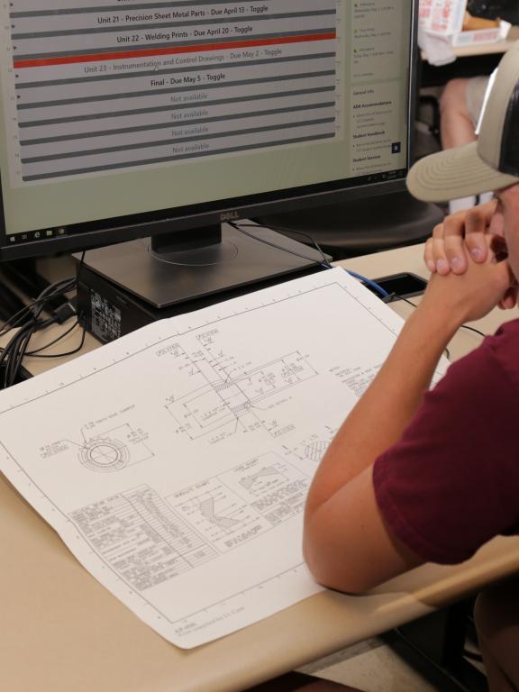 Student looks over blueprints at computer