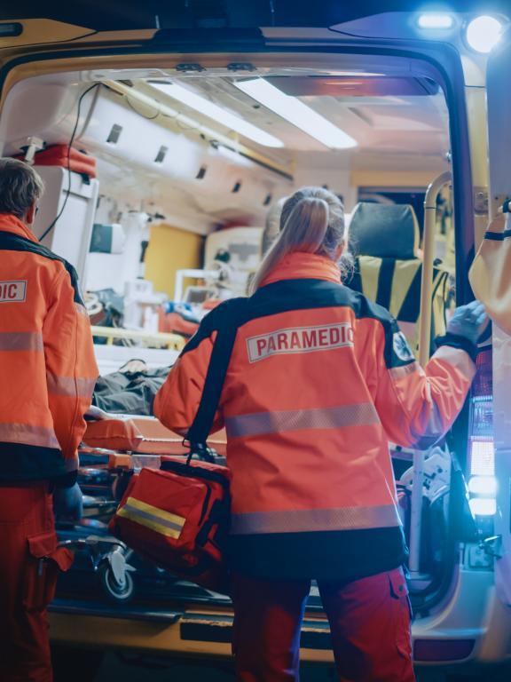 Emergency medical responders load back of ambulance at night