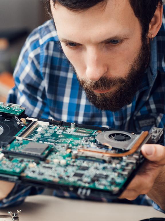 Male intently examines motherboard and electronic components