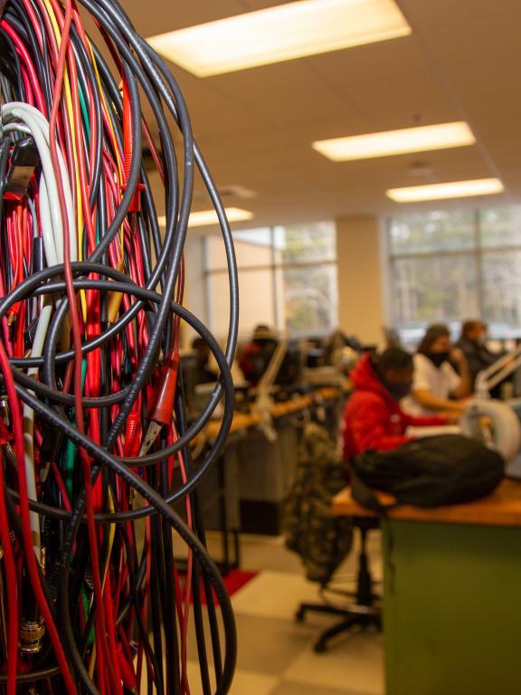 A mass of black and red wires in a classroom full of students
