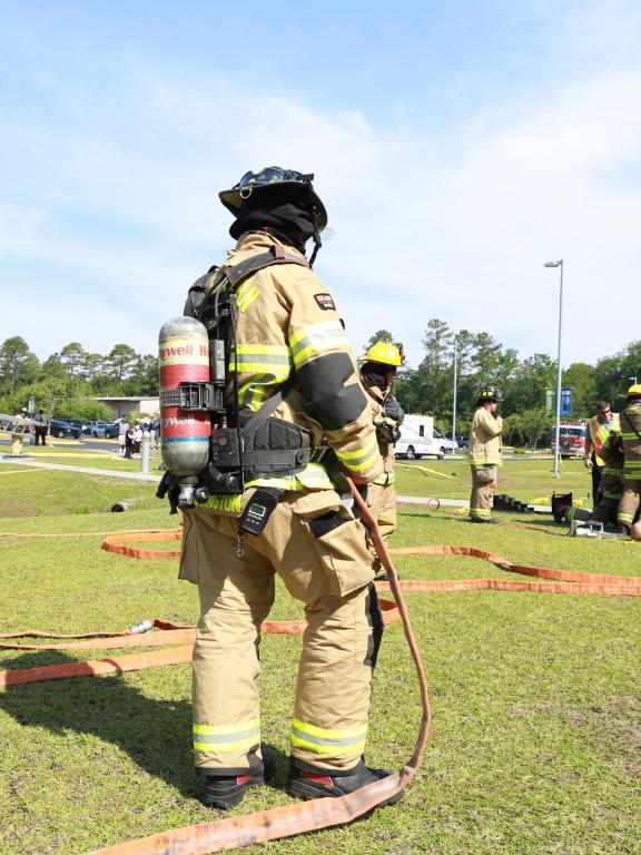 firefighter wearing full gear stands with hose during an emergency drill