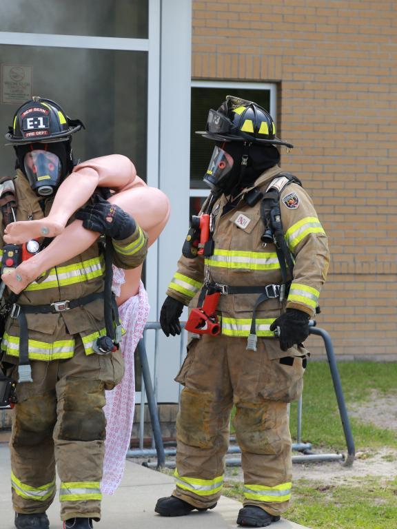 Firefighters practice rescuing and carrying dummy from building