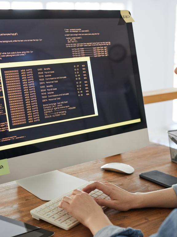Female IT worker looks at code on desktop computer