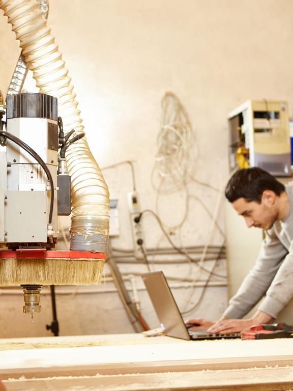 Male works on laptop next to mechatronic machinery