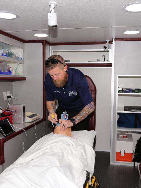 EMT instructor demonstrates CRP on training dummy in ambulance simulator