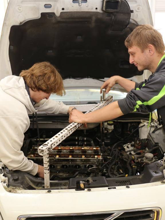 Two automotive students work on a car