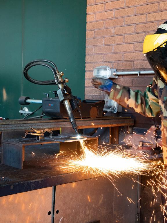 Two welding students practice welding outside