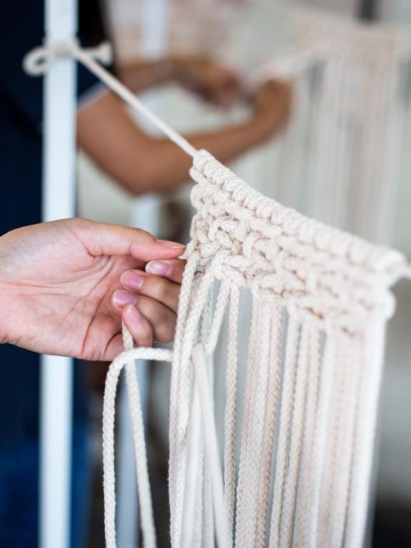 Two people work on macrame projects.