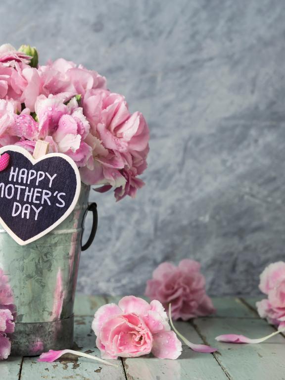Tin bucket containing pink flowers and heart-shaped tag that says Happy Mother's Day