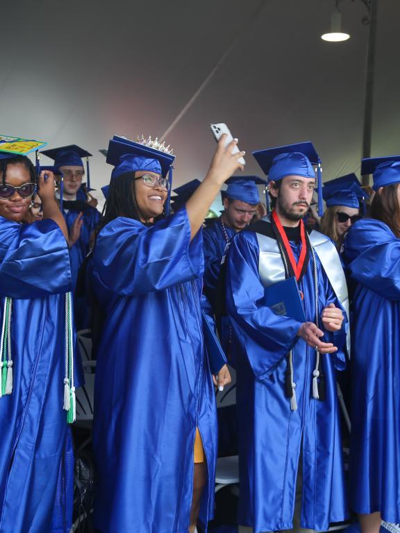 2023 graduates in caps and gowns moving tassel over