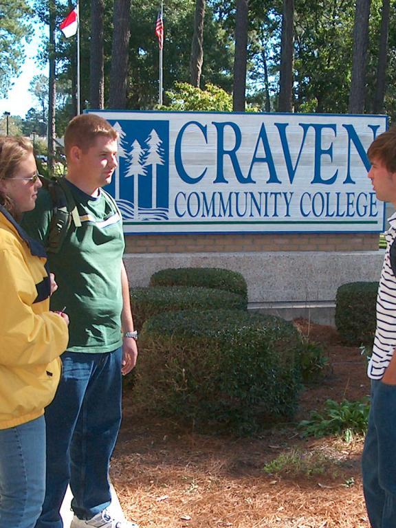 Three students standing outside by the Craven CC entrance sign in 2000s