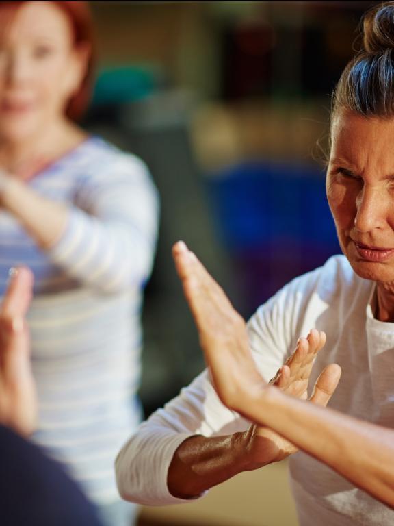 Elderly women hold up hands defensively in self-defense training