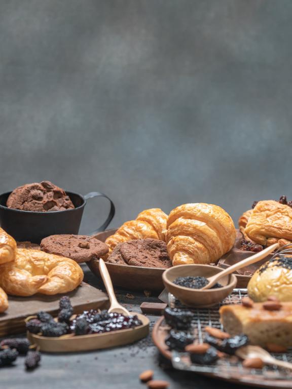 Assortment of bakery goods, croissants, and chocolate chip cookies on wooden table