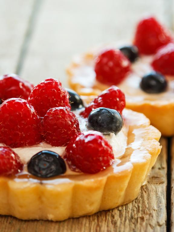 Two fruit tarts topped with blueberries and raspberries