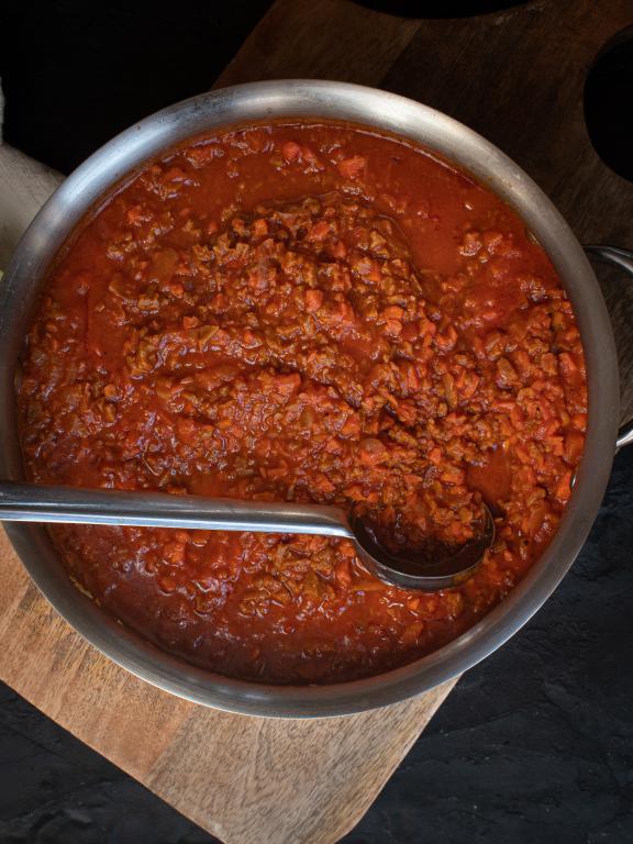 Pot of Bolognese sauce with silver serving spoon