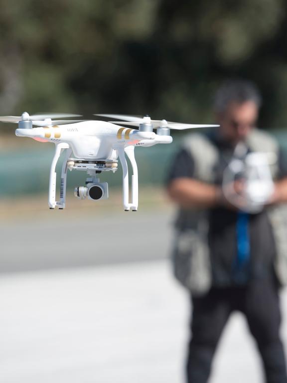 Close up of white drone hovering in front of male in tactical vest