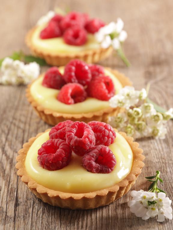 Three lemon tarts topped with raspberries