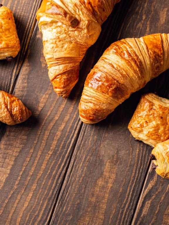 Top view of freshly baked sweet buns puff pastry with chocolate and croissants on wooden table