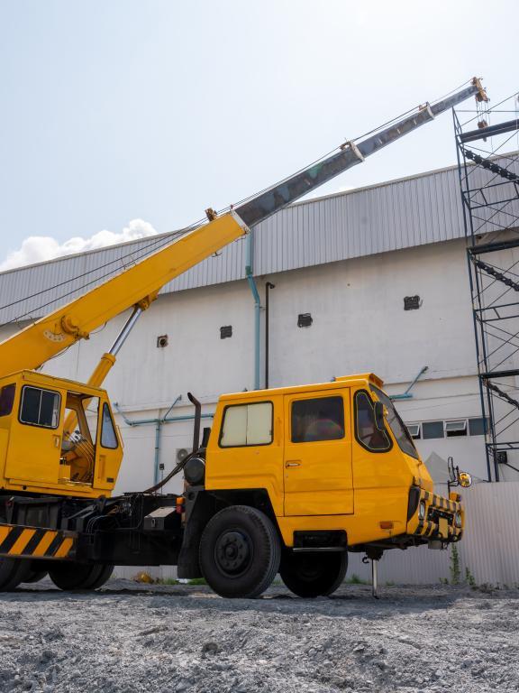 A yellow and black mobile crane at roof repair in construction site
