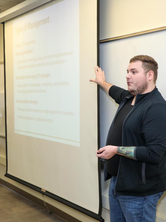 Instructor presenting a lesson on types of management in a classroom.