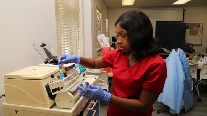 Phlebotomy student examines vials of blood