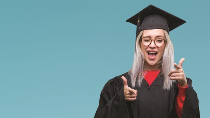 Happy female graduate pointing and winking at camera