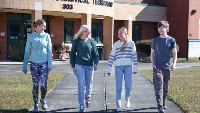 Four Craven Community College students walk together outside the Institute of Aeronautical Technology.