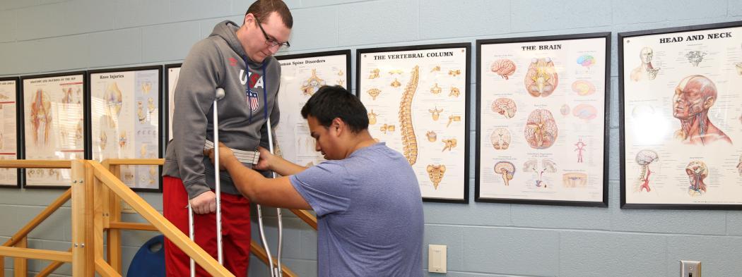 Physical Therapist Assistance program student helps another student on crutches 