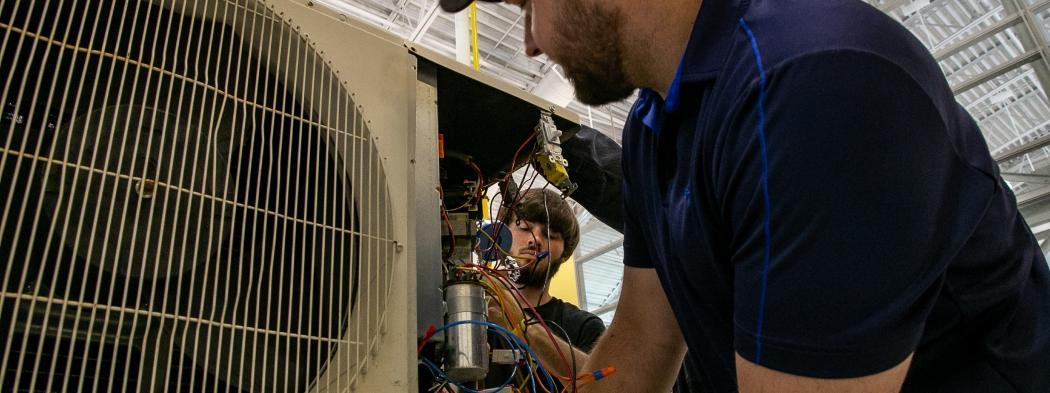 HVAC students work on an air conditioning unit