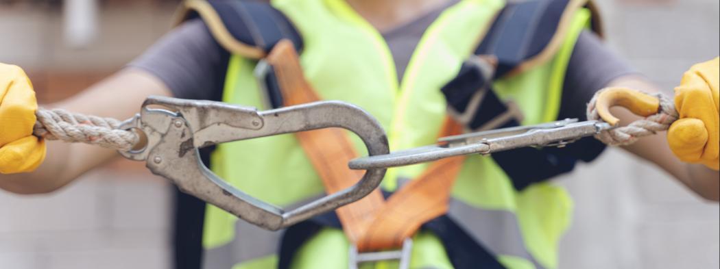 Construction worker makes sure harness is securely hooked