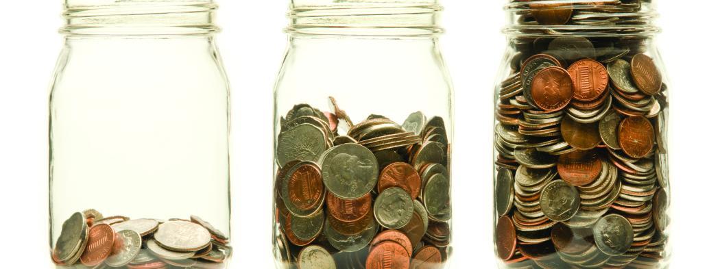 Three glass jars increasingly filled with coins
