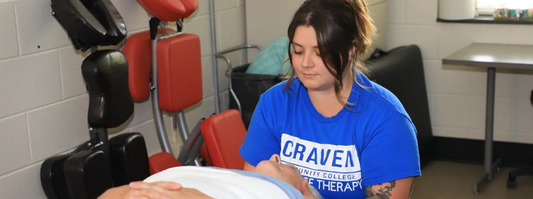 Female massage therapy student practices techniques on another female student