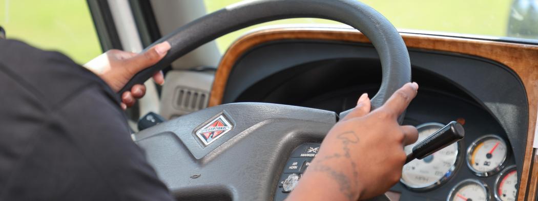 Transportation student practices driving a commercial vehicle during hands-on training.