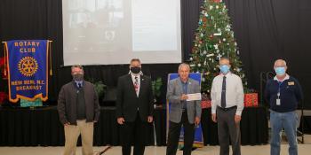 College officials and New Bern Rotary Club members posing with donation check by Christmas tree