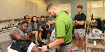 Students in Craven CC’s Physical Therapist Assistant (PTA) program observe as Dr. Dan Friedlander, PTA program coordinator and instructor, demonstrates how to perform a therapeutic ultrasound for deep heating of tissues in the knee. (Photo by Meredith Laskovics)