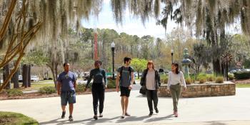 two males and three female students walking outside