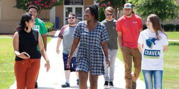 Group of happy students walking down path on campus