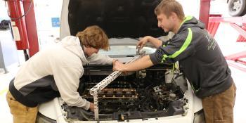 Two automotive students work on a car