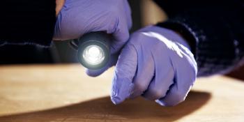 Person wearing latex gloves and holding a flashlight