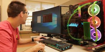 Male IT student works on computer with neon lighted cooling components