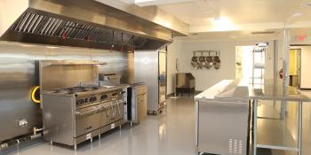 View of the Volt Center Kitchen range, refrigerator, prep station, pots and pans on the wall