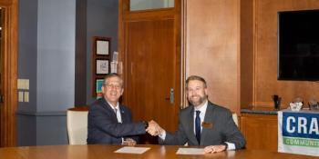 Two men sitting at table shake hands