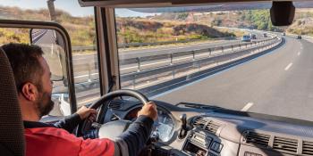 Man is behind the wheel of a semi truck on a highway