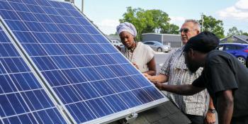 Students and instructor in the Solar Photovoltaic program look at solar panel