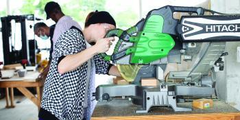 Female carpentry student uses a table saw