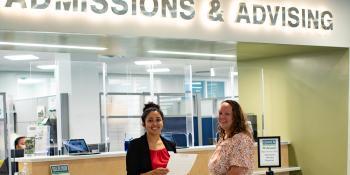 A Craven CC staff member and student smile outside the Admissions & Advising counter