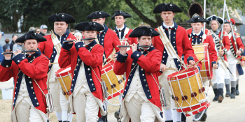 Men dressed as colonial soldiers play fife and drum