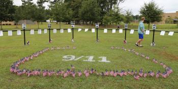 Tiny American flags staked in the ground around white spray-painted "9/11" for September 11th remembrance event