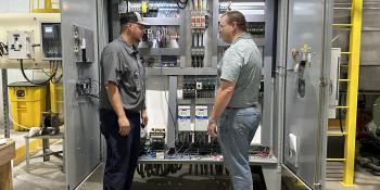 Chatsworth employees Cody Marshall and Stephen Calabro stand in front of an industrial control panel